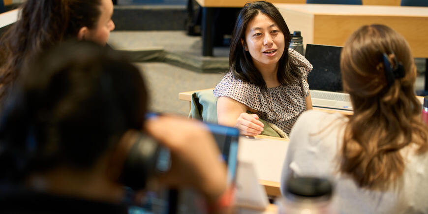 Megan Hung sits in a lecture hall. She turns around to talk with three friends.